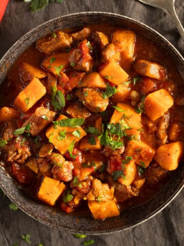 pork and sweet potato stew sprinkled with parsley in a serving bowl.