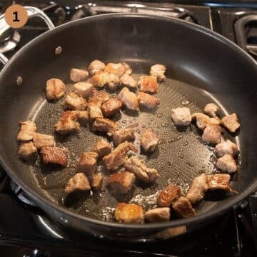 searing pork cubes in a heavy bottomed pan.