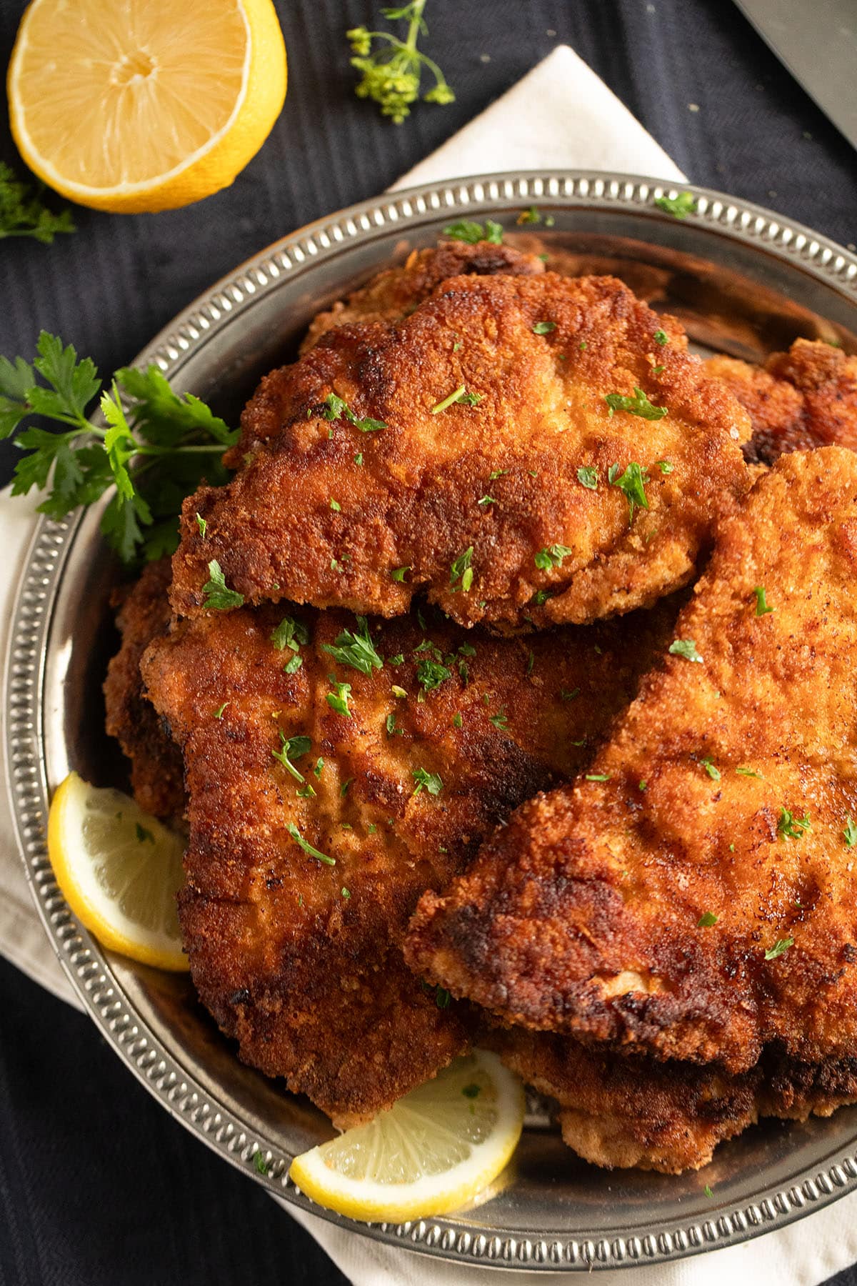 many golden brown schnitzels made with turkey breast on a silver plate.