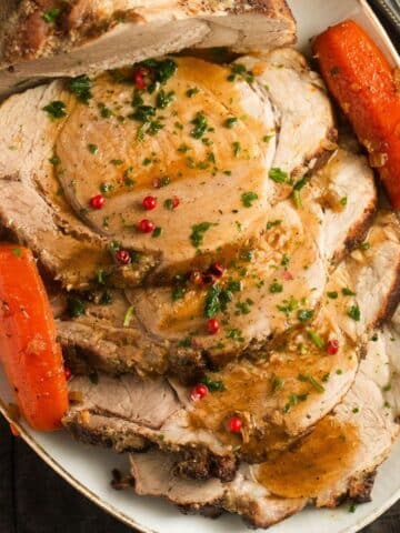 dutch oven pork roast sliced on a platter and served with carrot halves.