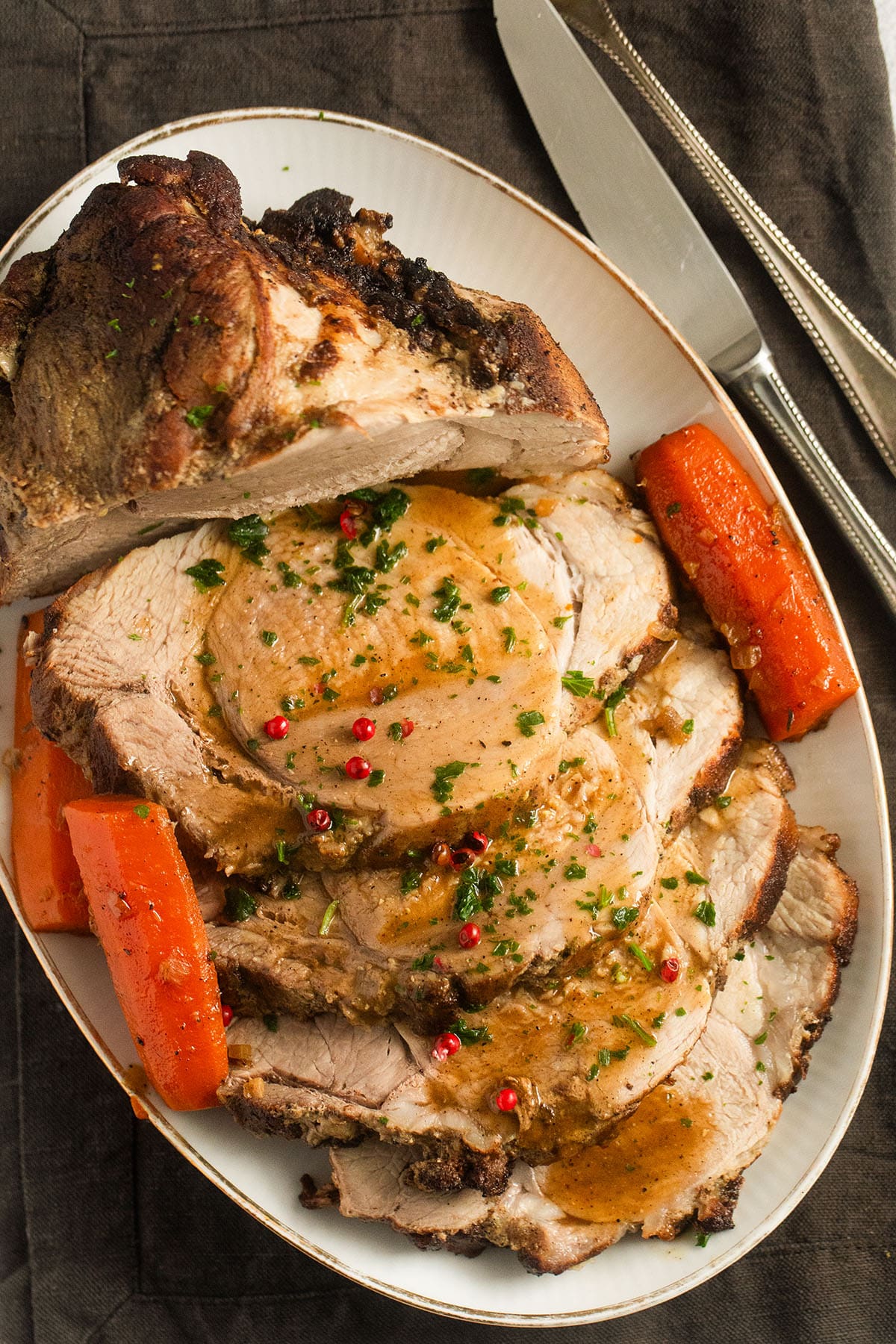 pork roast cooked in a dutch oven and sliced on a platter with gravy.