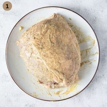 raw piece of pork roast seasoned and covered with mustard.