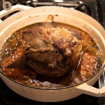 pork roast with carrot pieces and gravy in a dutch oven pot.