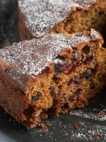 a slice of fruitcake with raisins, cranberries and other dried fruit.