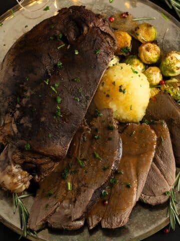 sliced venison roast served with potato dumpling, brussels sprouts and gravy.