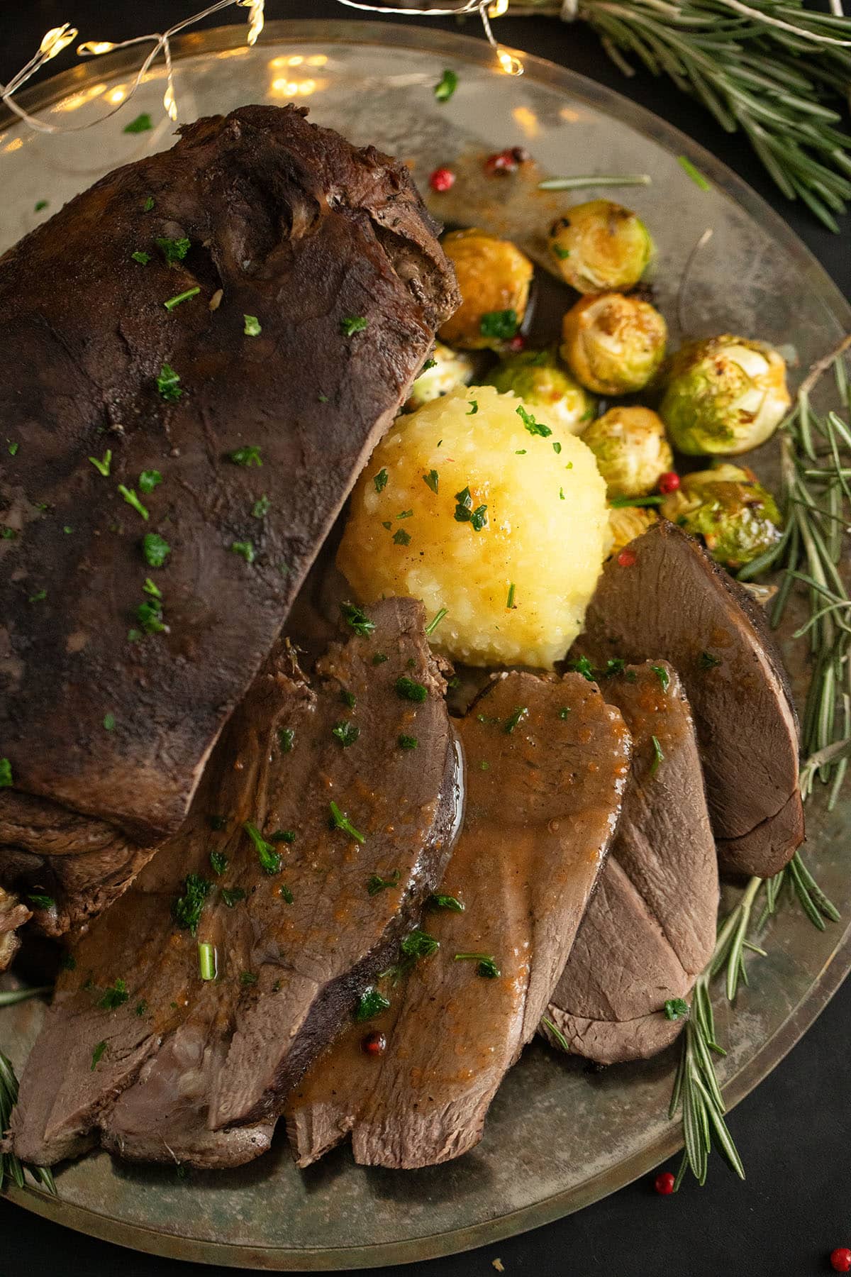 venison roast served with gravy, sprouts and dumplings on a vintage platter.