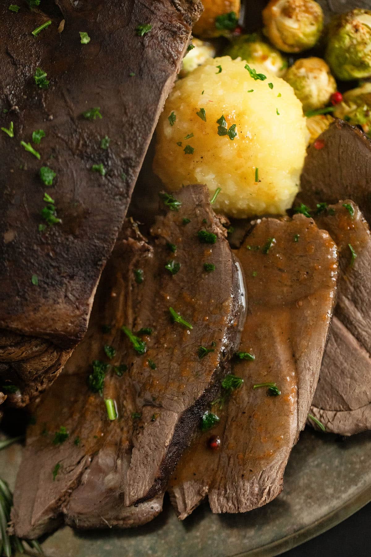 sliced deer roast with potato dumplings and gravy.