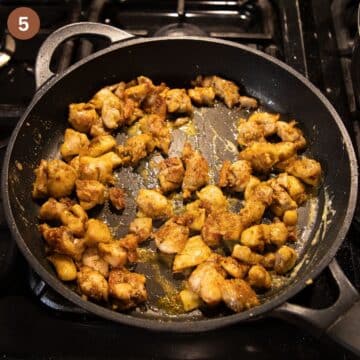 golden chicken pieces sprinkled with flour in a pan.