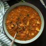 red lentil bacon soup in a bowl with a spoon in it.