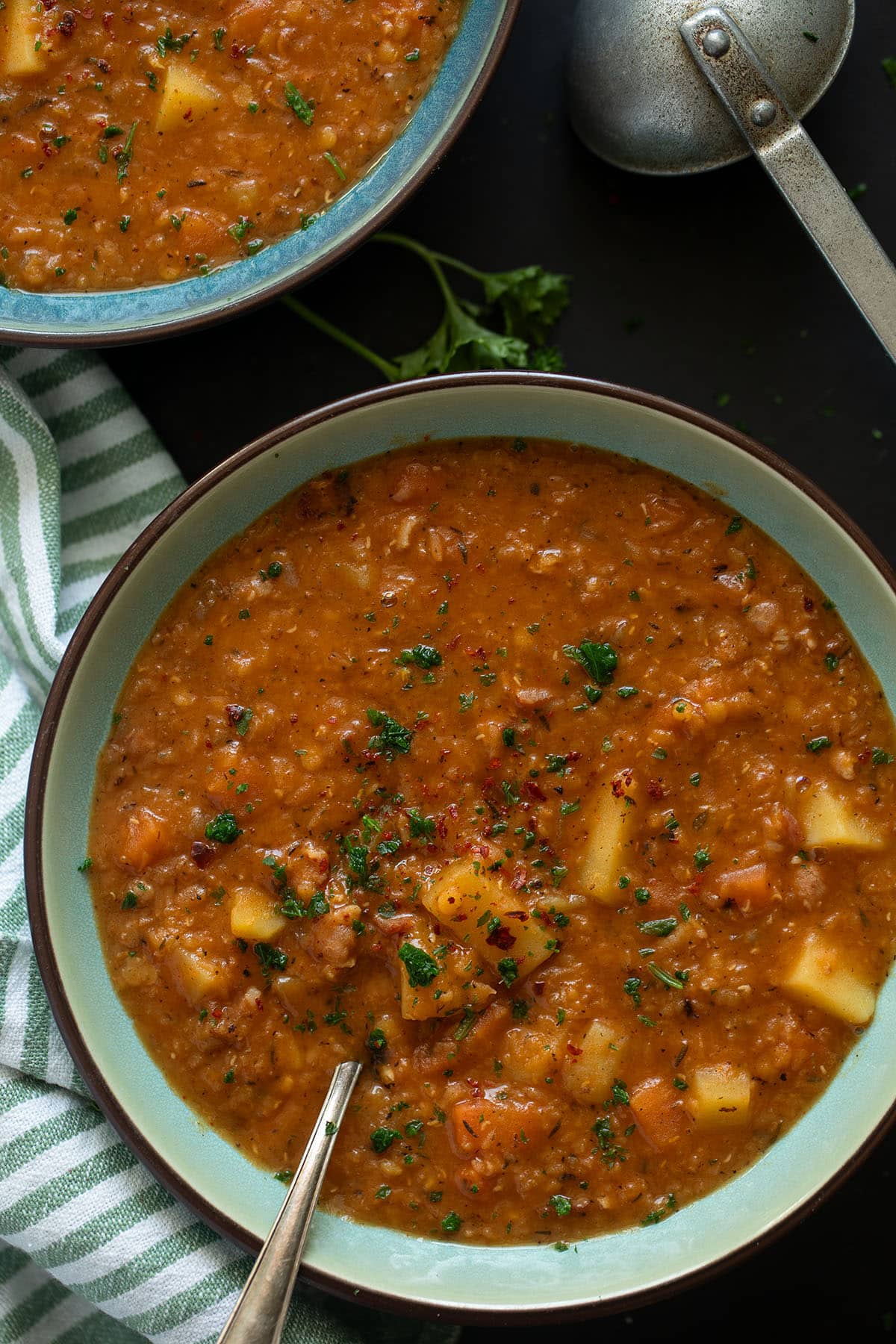 two bowls of thick soup with red lentils, bacon and vegetables.