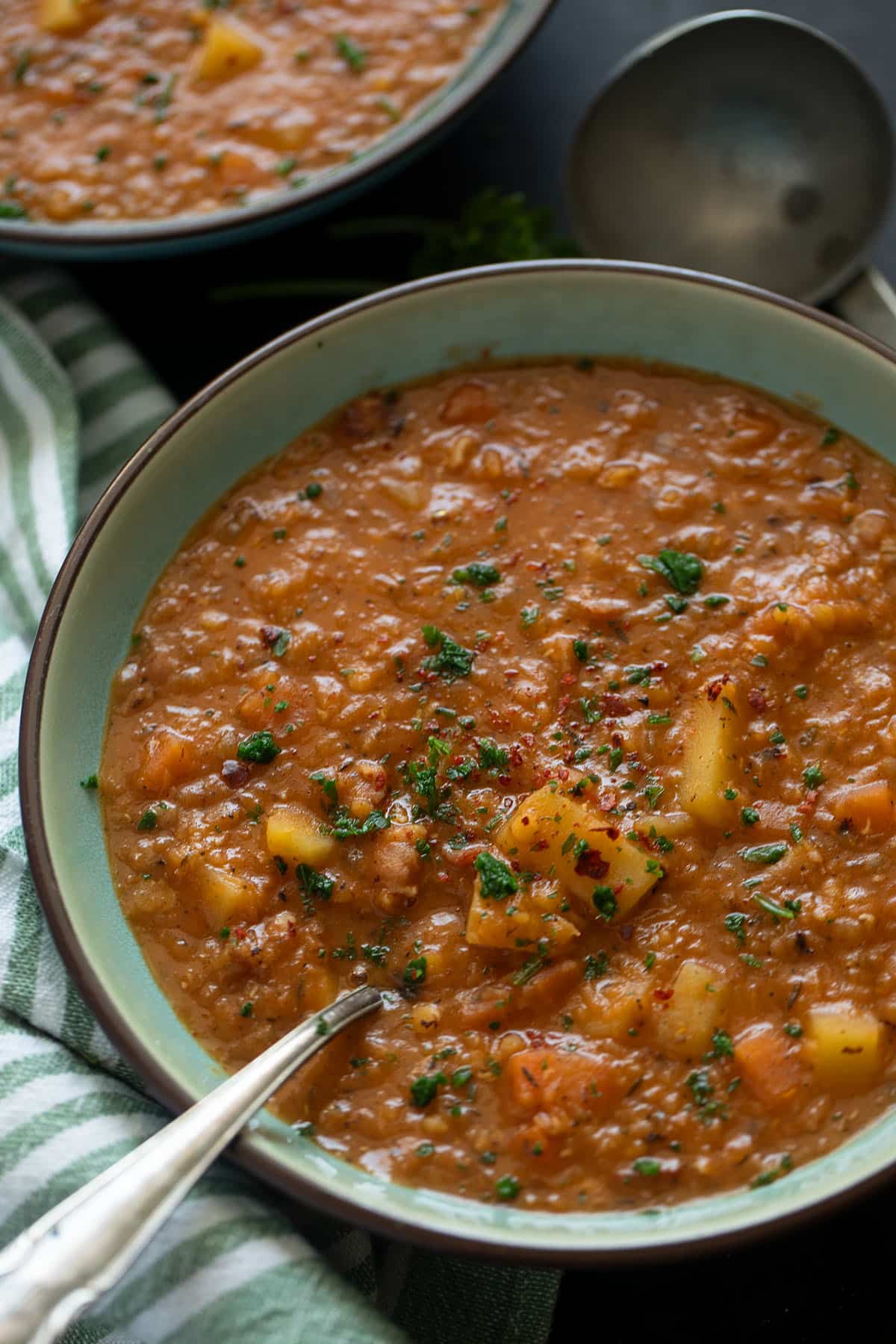 bacon and red lentil soup in a bowl with a spoon in it.