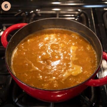 thick lentil soup simmering in a large pot on the stove top.