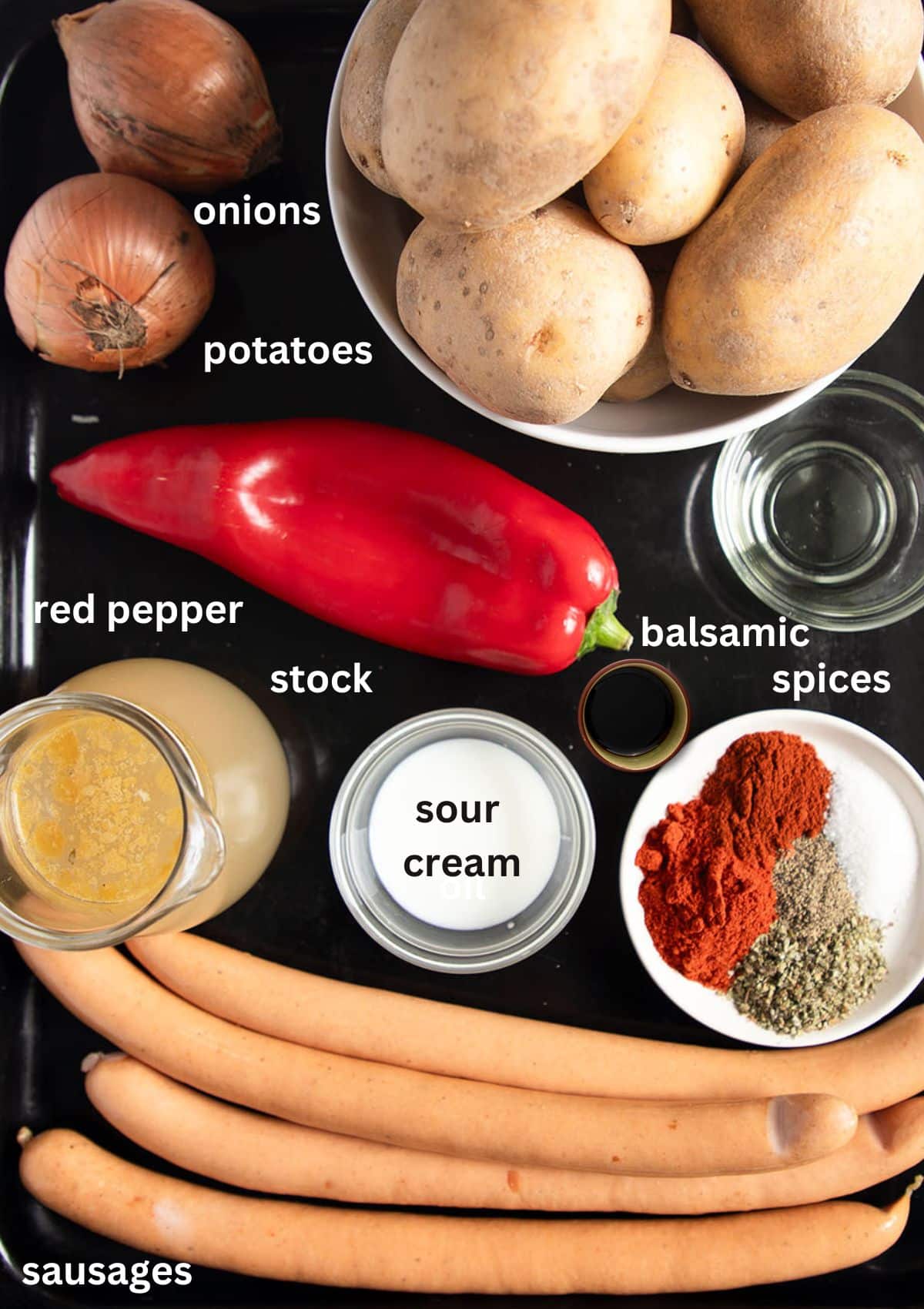 listed ingredients for making goulash with wiener sausages, potatoes, pepper, stock, onions and spices.