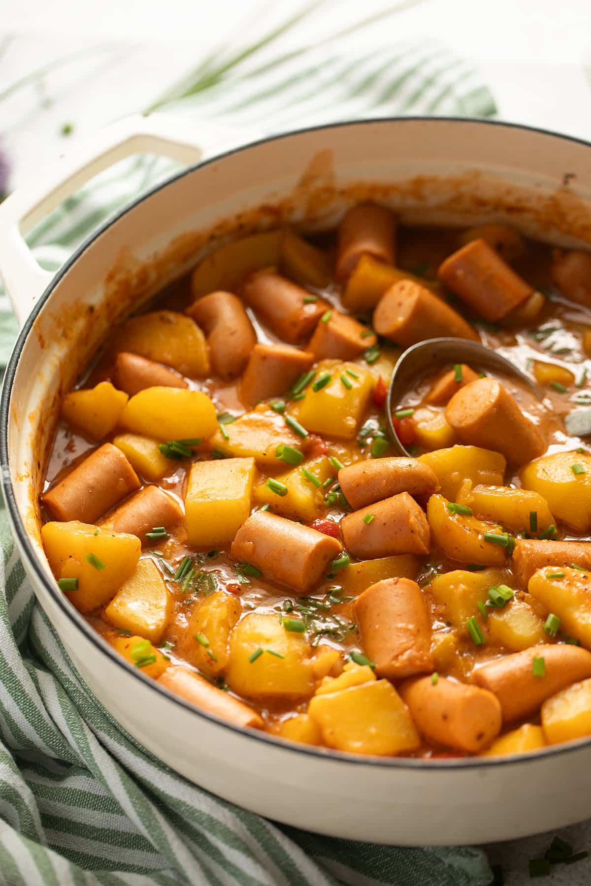 sausage goulash with potatoes and peppers in a dutch oven.