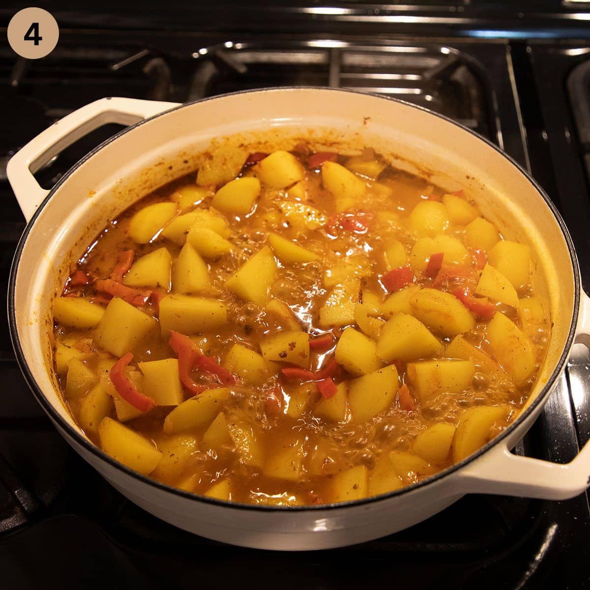 simmering potatoes in stock for making stew in a large pot.