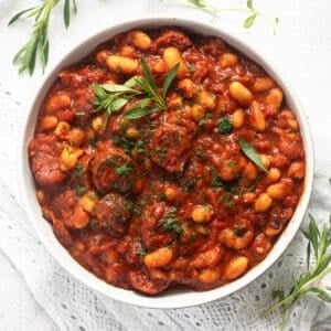 thick butterbean and chorizo stew topped with fresh thyme in a bowl.