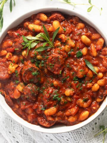 thick butterbean and chorizo stew topped with fresh thyme in a bowl.