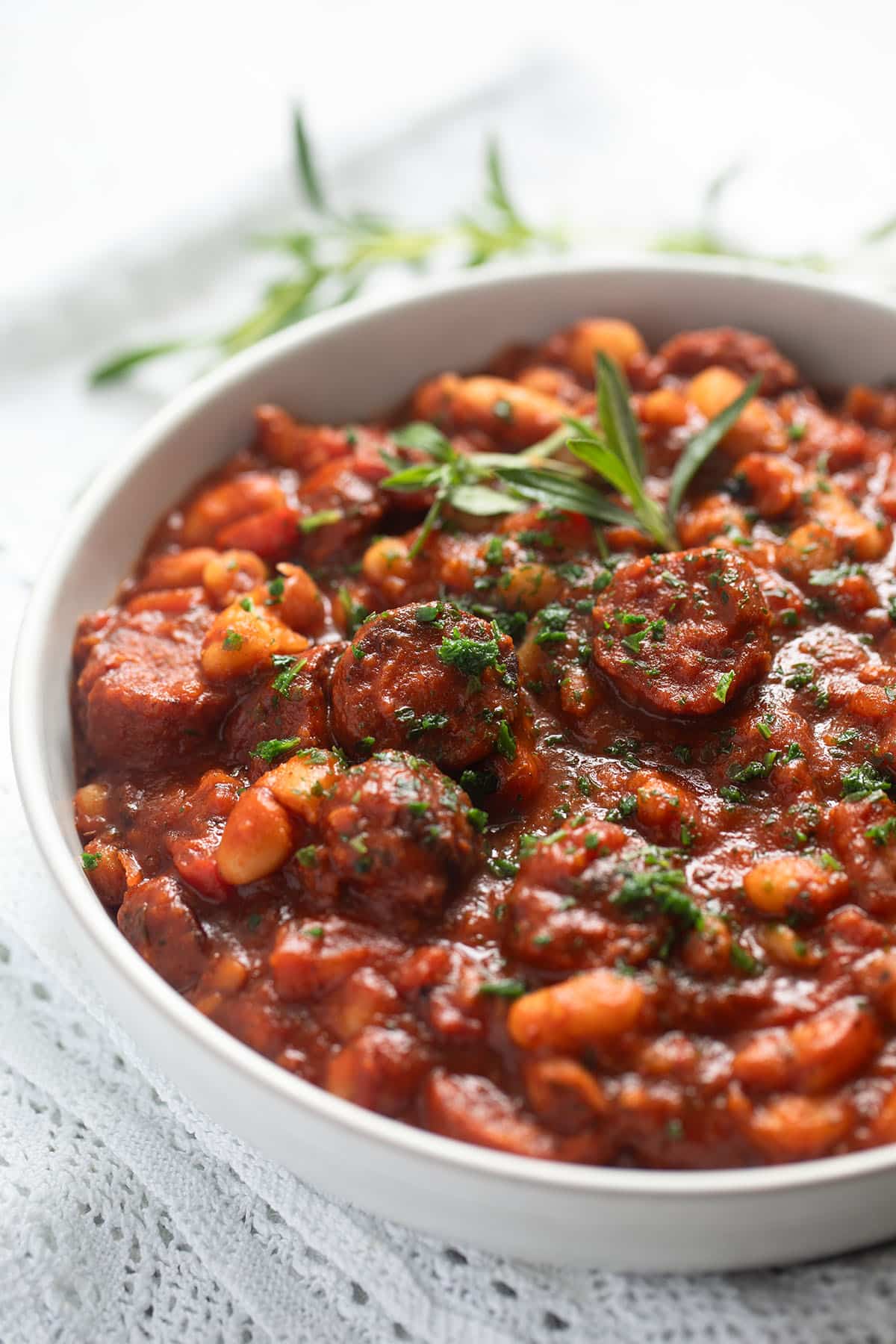 butter bean and chorizo stew topped with fresh herbs in a large bowl.