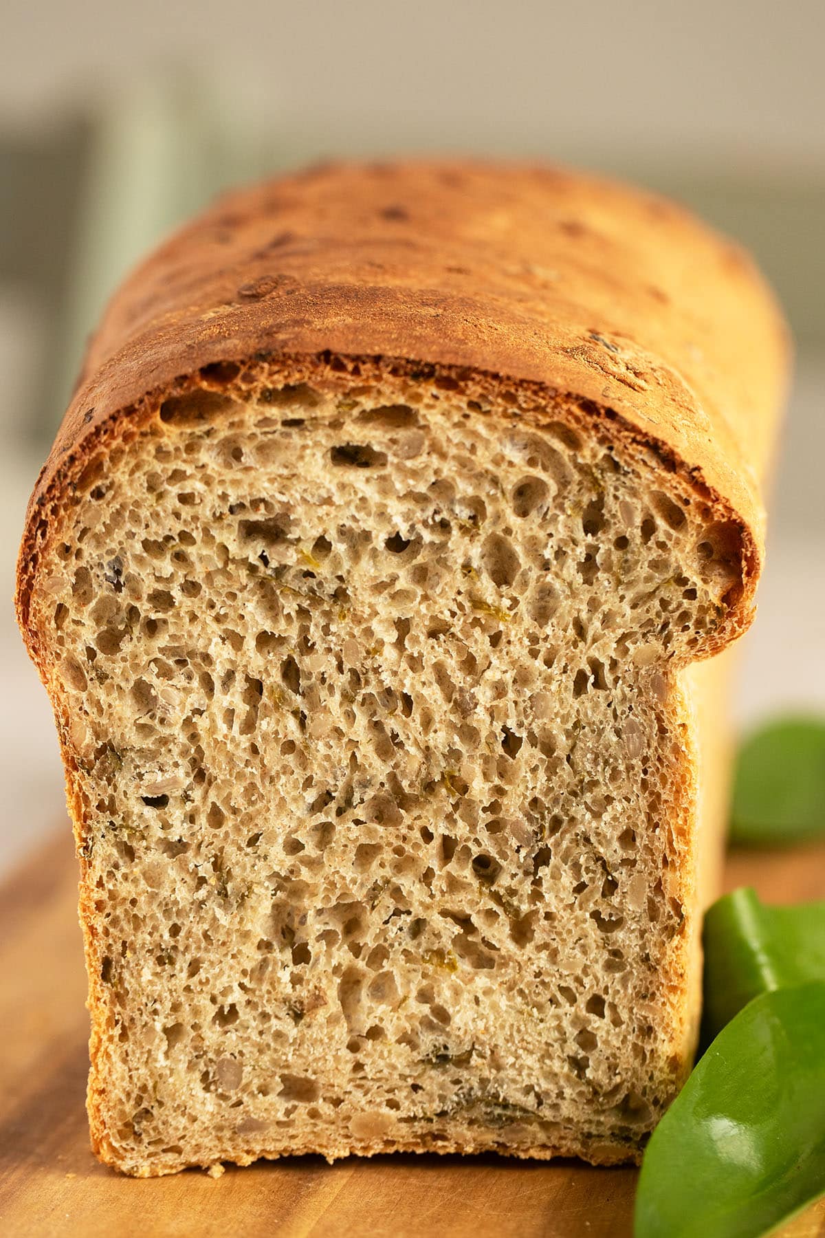 a loaf of bread with whole wheat and chives on a cutting board.