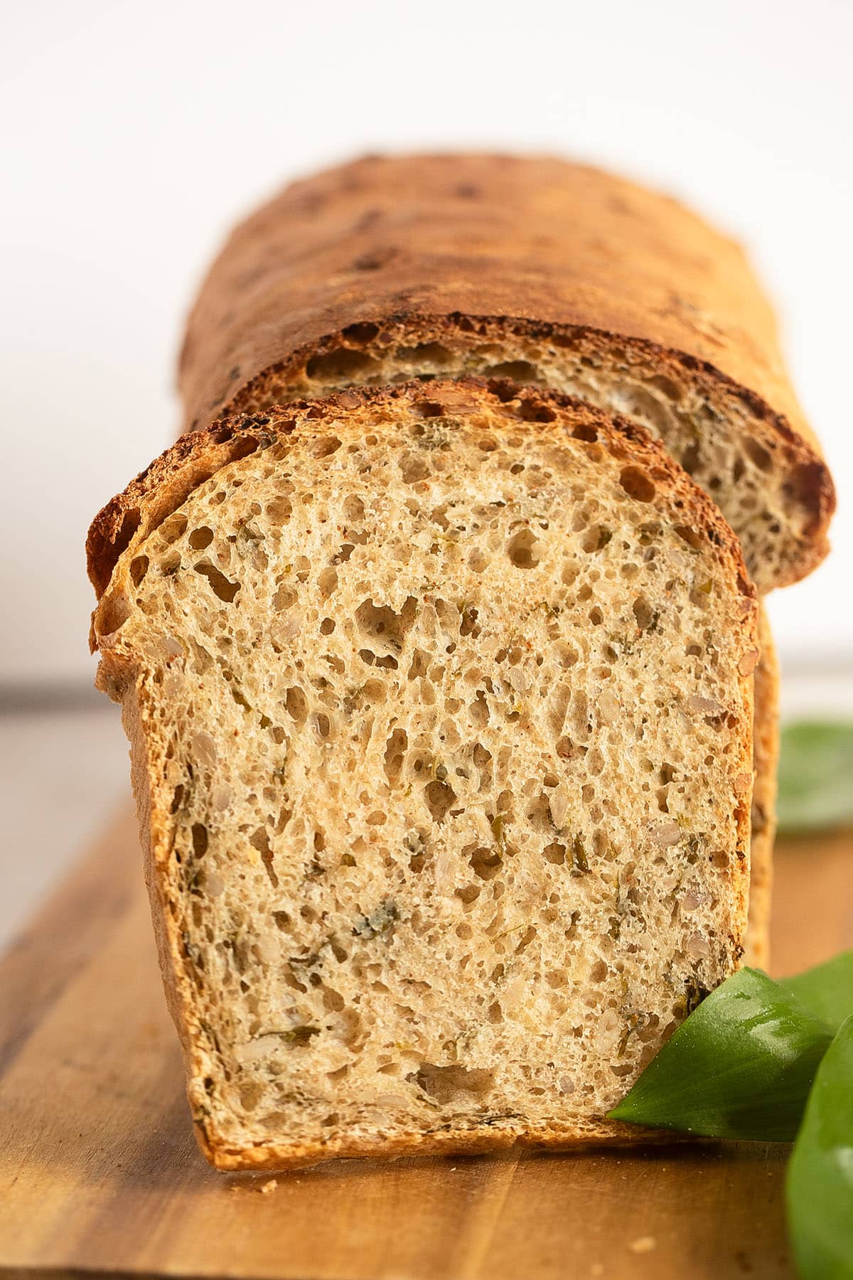 chive bread with a slice leaning against the loaf of bread.