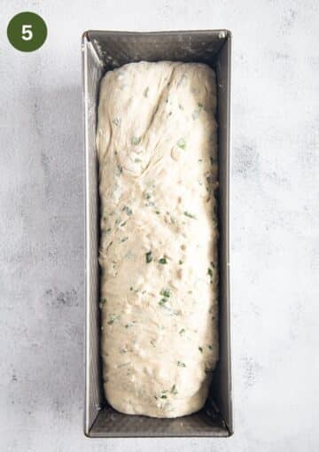 bread dough with chives in a loaf pan before rising.