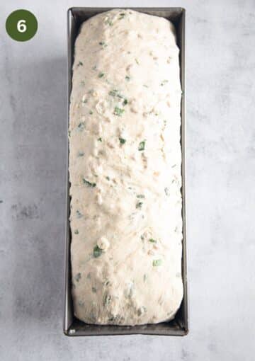 bread dough with chives in a loaf pan before rising.