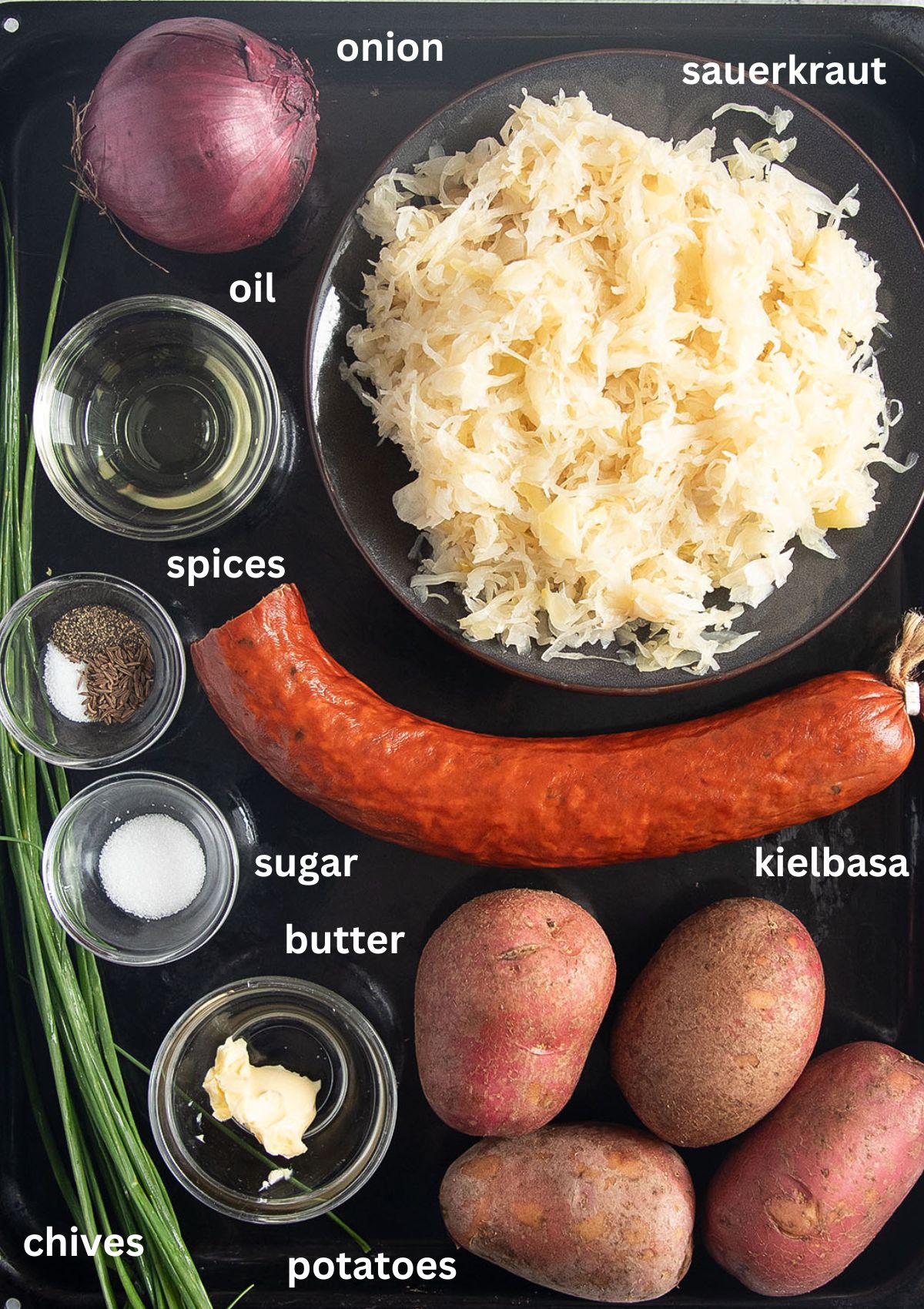 listed ingredients for cooking a dish with kielbasa sausage, sauerkraut and potatoes.