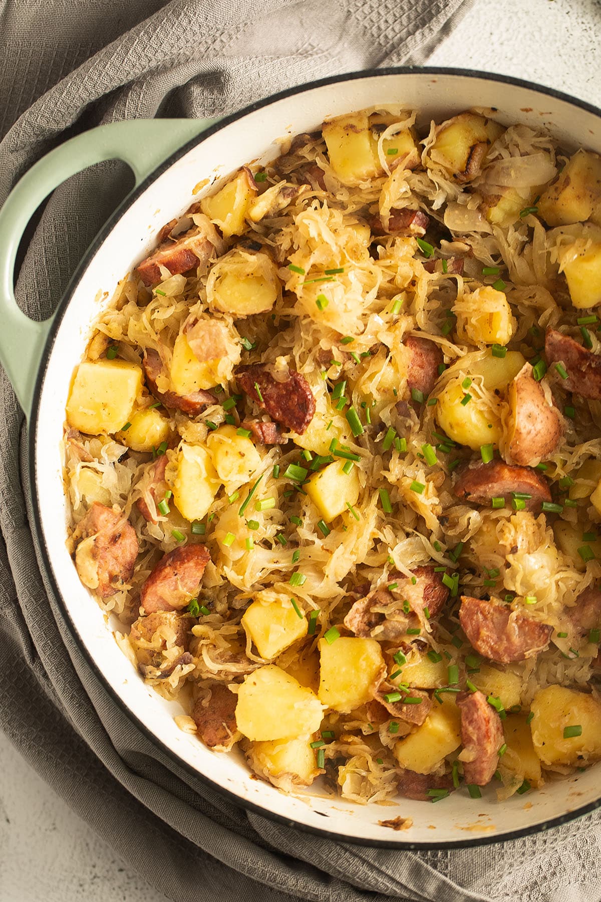 kielbasa, sausages and potatoes sprinkled with chives in a dutch oven.