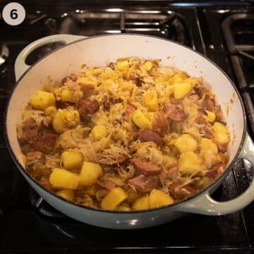 potato chunks, sausage pieces and sauerkraut simmering in a pot.