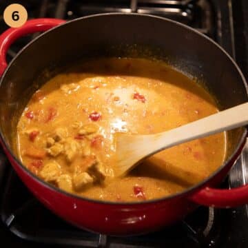 stirring chicken rice and paprika soup with a wooden spoon.