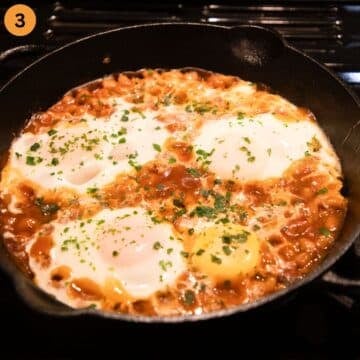eggs setting in a skillet on top of baked beans.