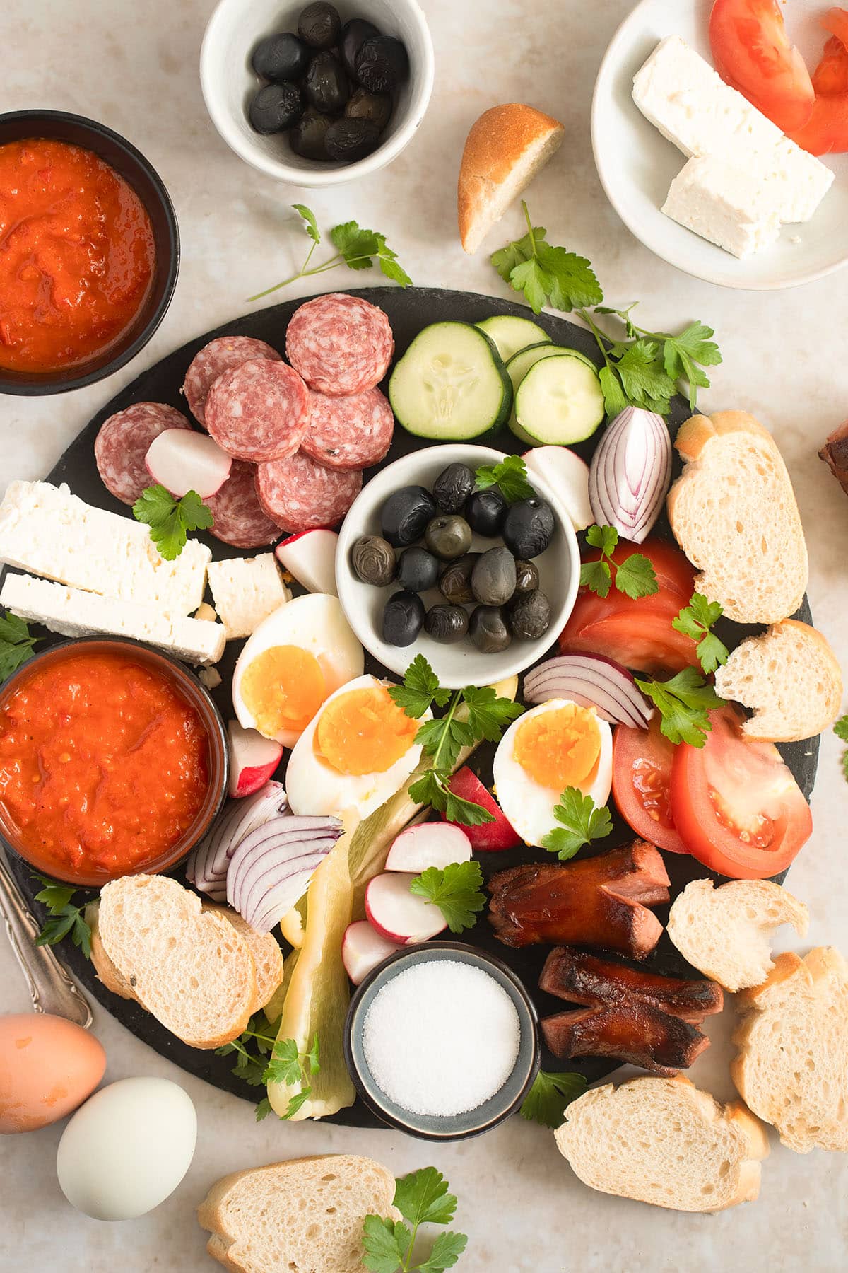 platter with balkan breakfast, many slices of bread and bowls of dip around it.