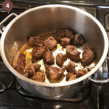 browning lamb pieces in a large pot.