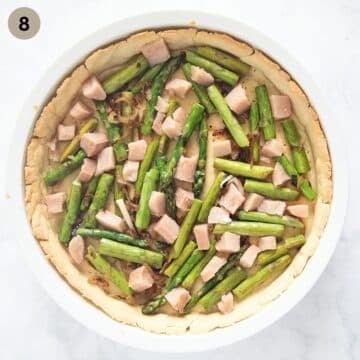 assembled quiche with salmon cubes, asparagus and onions in a baking dish.