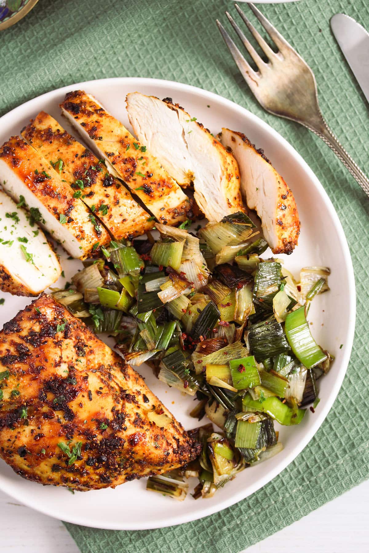 two grilled chicken breasts with paprika served with cooked leeks.