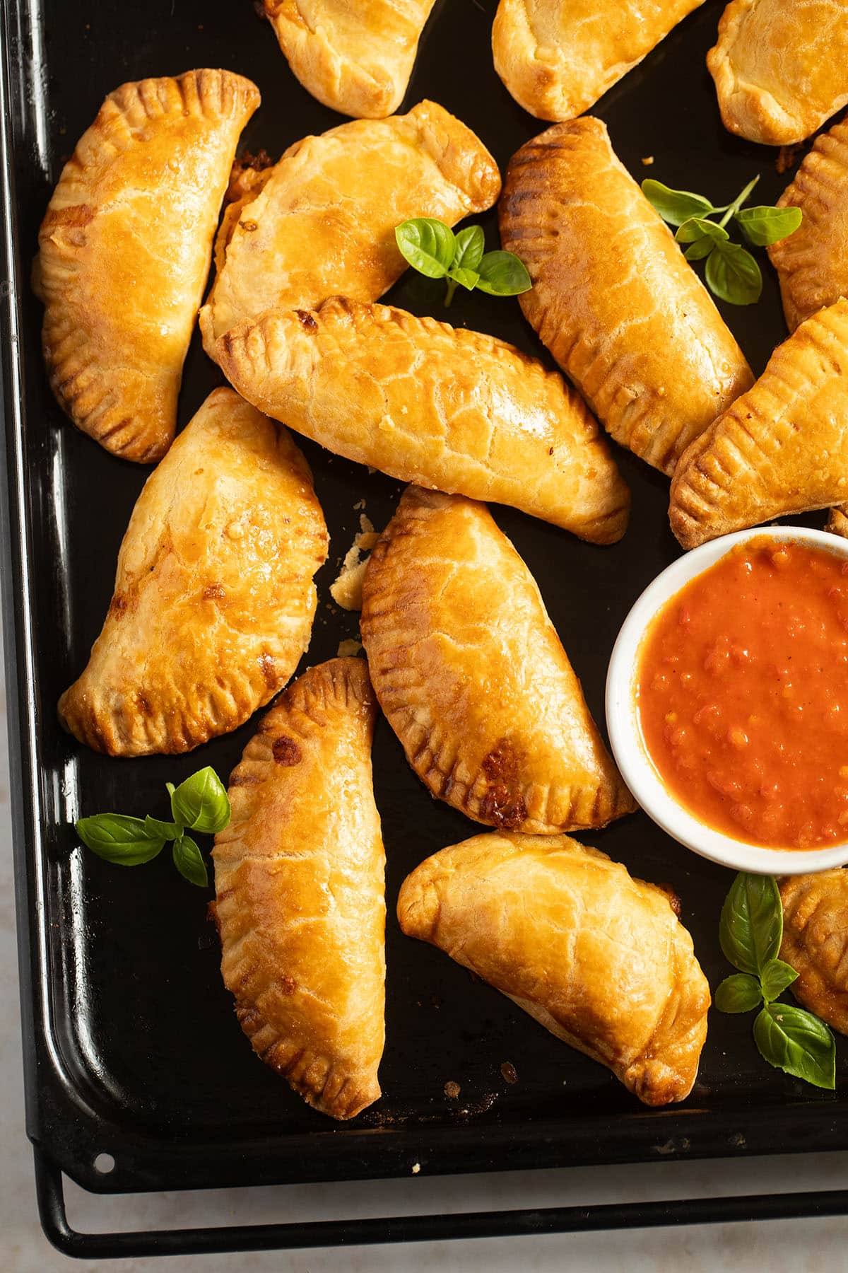 golden baked empanadas filled with ham and cheese and a bowl of red salsa.