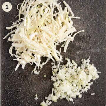 finely sliced white cabbage and chopped onion on a cutting board.