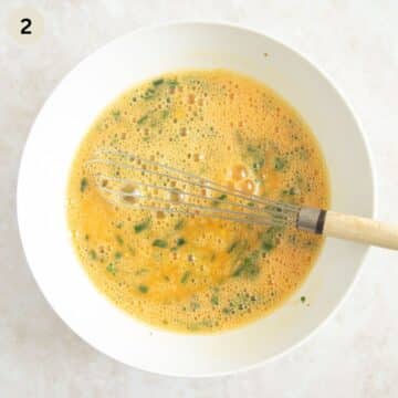 whisking eggs with seasoning and spices in a bowl.