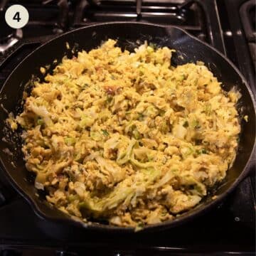 cabbage and eggs scrambled in a skillet on the stove top.