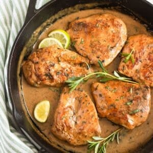 chardonnay chicken, lime slices and fresh thyme in a cast iron skillet.