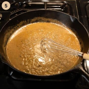 mixing butter pieces with a whisk in white wine sauce in a skillet.