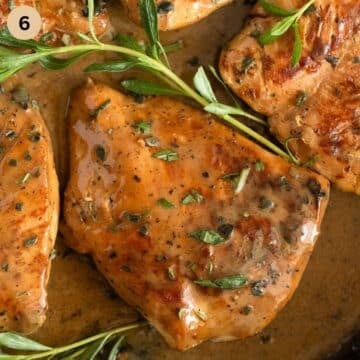 chicken breast pieces in creamy sauce with thyme sprigs on top.