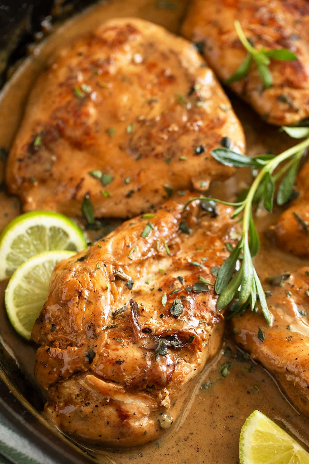 two large chicken breasts with chardonnay sauce and lime slices.