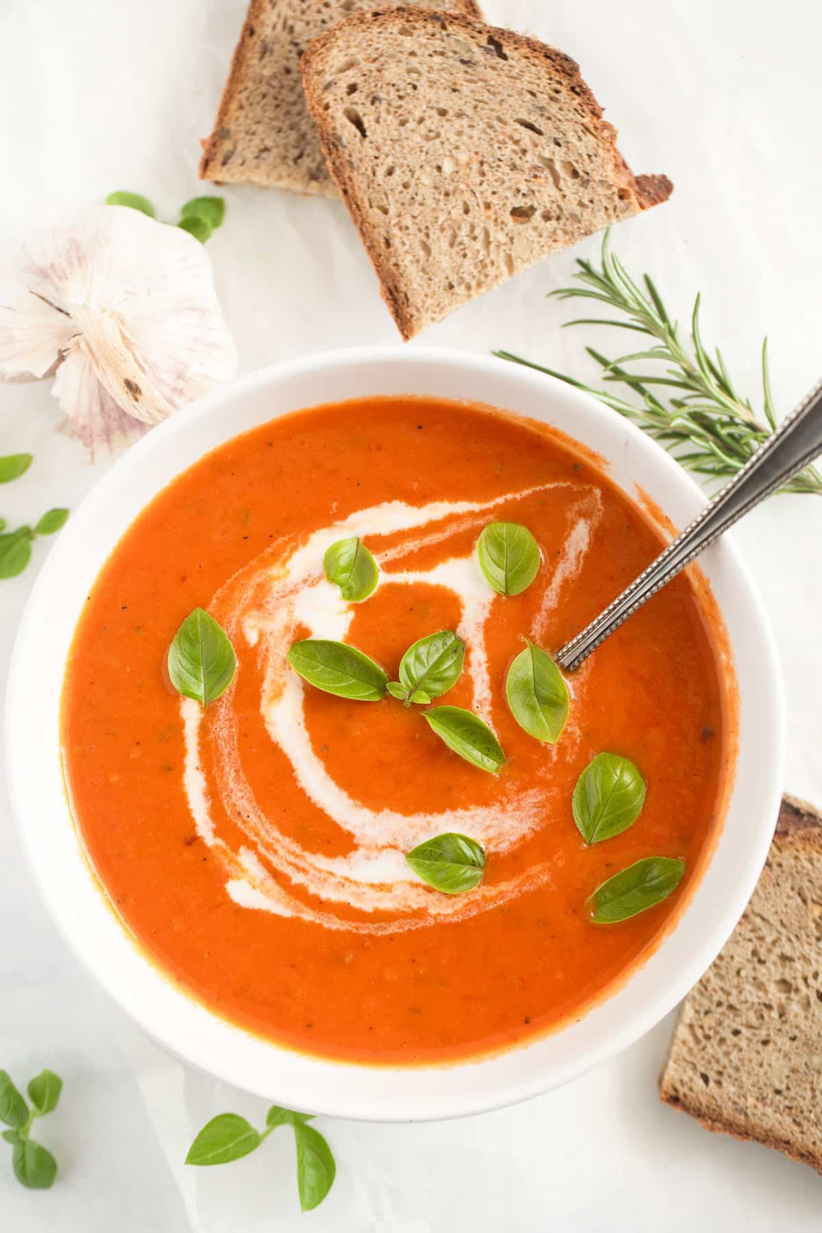 soup made with roasted tomatoes and garlic in a bowl, bread slices on the side.