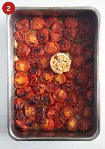 roasted tomatoes and a bulb of garlic in a roasting pan.
