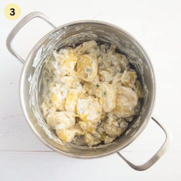 cooked potato slices mixed with sour cream in a pot.
