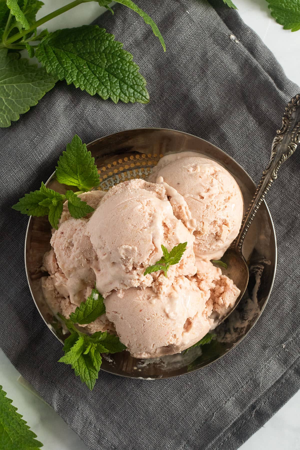 scoops of strawberry and rhubarb ice cream on a small plate.