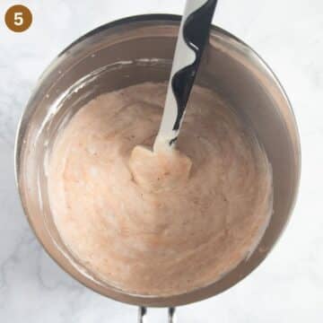 folding whipped cream in rhubarb and strawberry mixture to make ice cream.