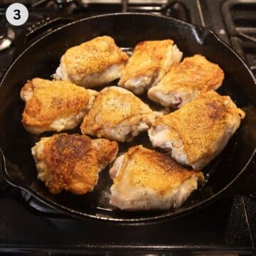 eight seared chicken thighs with golden crispy skin in a skillet.