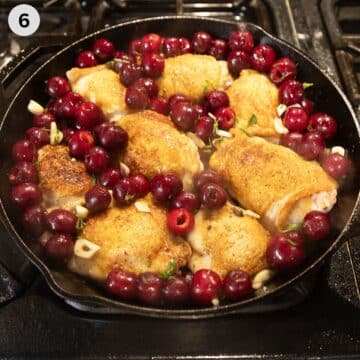 chicken thighs sourrounded by cherries in a skillet before roasting in the oven.